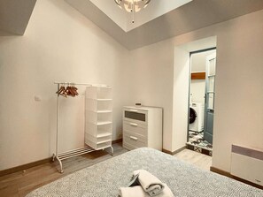 Ein Schlafzimmer mit Bett, Kleiderschrank, Wäscheständer und begehbarem Kleiderschrank.