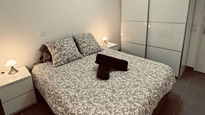 Une chambre à coucher comprenant un lit, deux tables de chevet, une commode et une armoire.