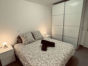 A bedroom with a bed, two bedside tables, a nightstand, and a wardrobe. - T2 Apartment with pool and AC - spacious lodging (Le Lavandou)