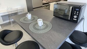 Une cuisine moderne équipée d’un four à micro-ondes, de deux tasses blanches et d’un tabouret de bar.