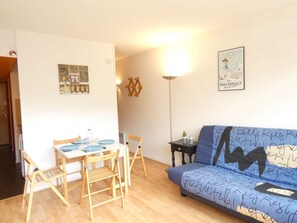 A small living area with a sofa, a dining table with chairs, and a lamp. - Cozy studio with mountain view - 4 guests (Piau-Engaly)