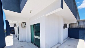 Ein Balkon mit Fliesenboden, einer Schiebeglastür und einer Klimaanlage.