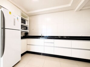 A modern kitchen with white cabinets, a black countertop, and stainless steel appliances. - Mont Blanc by LikeHome (Bombinhas)