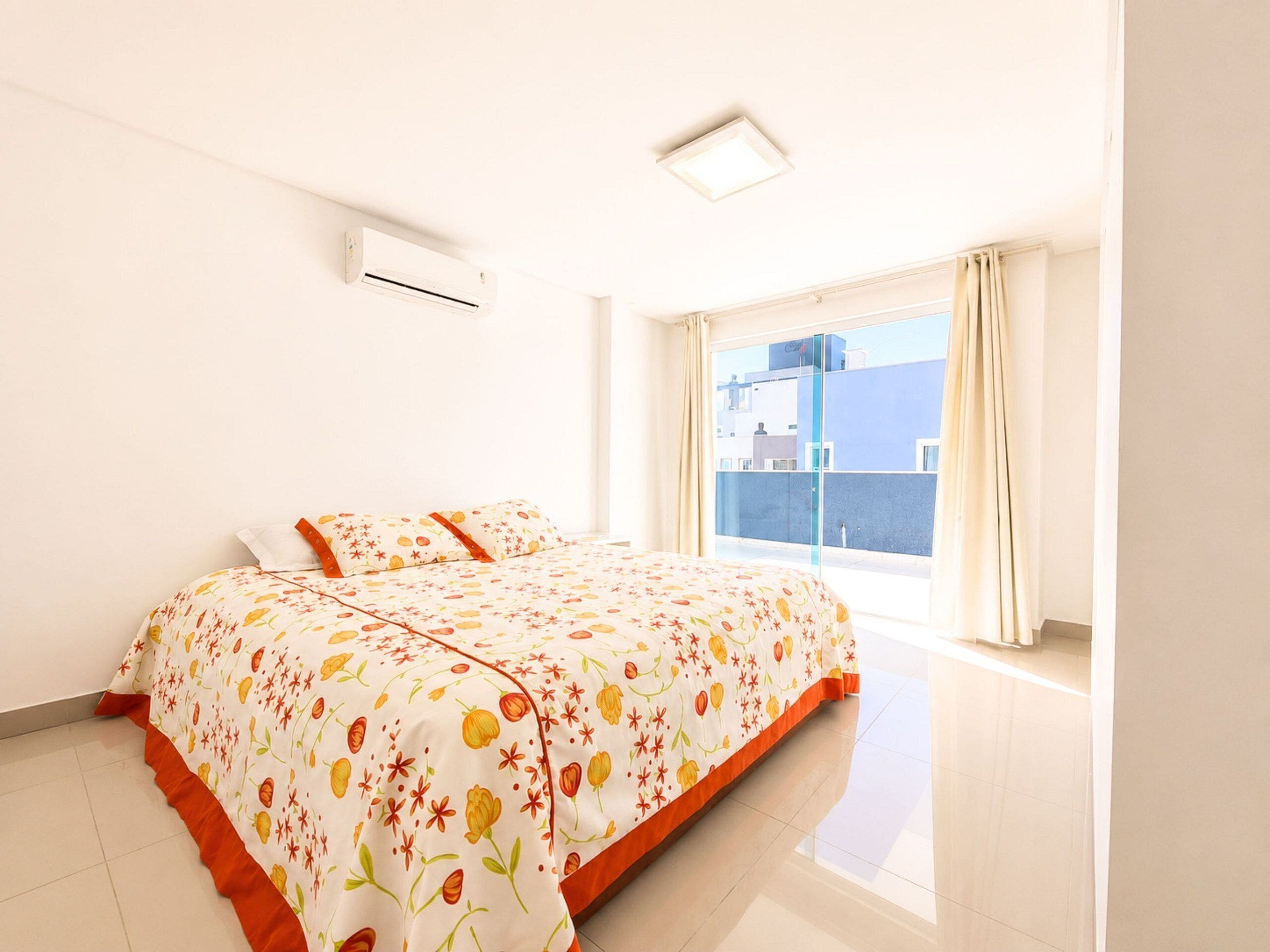 Un dormitorio con una cama, una ventana con cortinas y un equipo de aire acondicionado.
