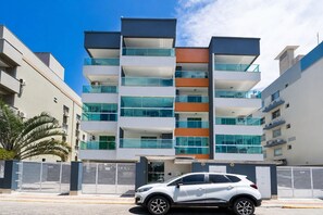 Un immeuble résidentiel à plusieurs étages, doté de balcons, d’une entrée sécurisée et d’une voiture garée.