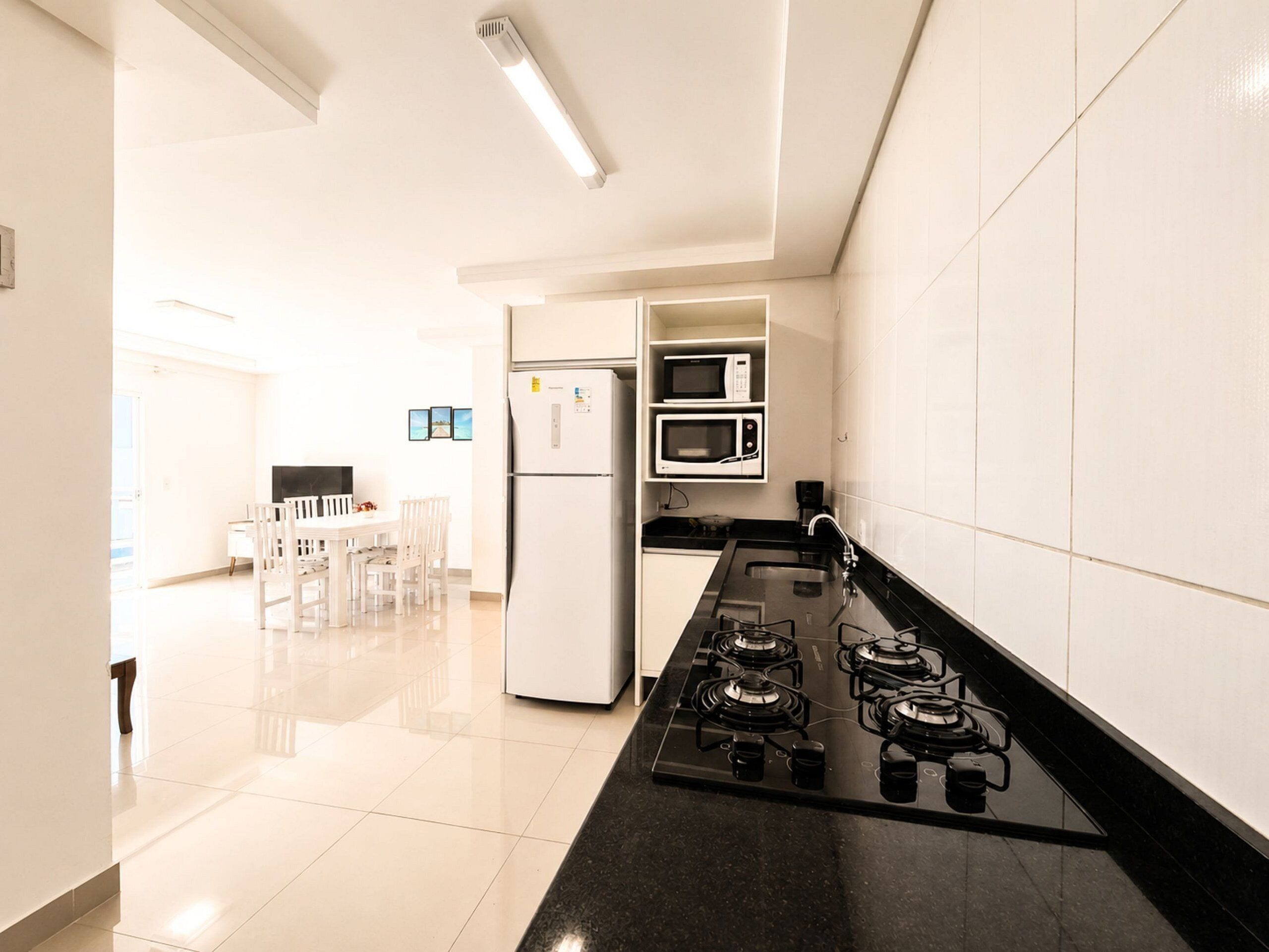 Uma cozinha moderna com fogão a gás, micro-ondas e geladeira.