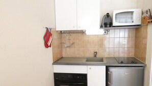 A compact kitchen with a built-in oven, a microwave, and a sink. - Cozy apartment facing south - 4 guests (Saint-Lary-Soulan)