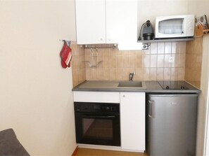 Eine kompakte Küche mit Backofen, Mikrowelle und Spüle.