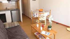 A compact living space with a kitchenette, a dining area, and a seating area with a sofa and a table. - Cozy apartment facing south - 4 guests (Saint-Lary-Soulan)