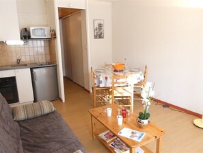 Ein kompakter Wohnraum mit Küchenzeile, Essbereich und einer Sitzecke mit Sofa und Tisch.
