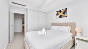 A hotel room with a bed, a nightstand, a lamp, and a painting on the wall.