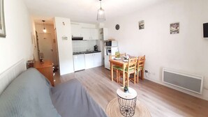 Um espaço de estar compacto com cozinha compacta, área de jantar e sofá.