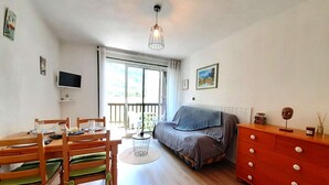 Um quarto com uma mesa de jantar, cadeiras, um sofá, uma televisão e uma janela com vista.