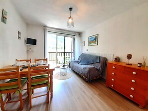 Ein Zimmer mit Esstisch, Stühlen, einer Couch, einem Fernseher und einem Fenster mit Blick.