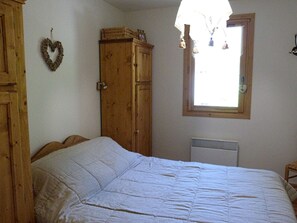 Ein Schlafzimmer mit einem großen Bett, einem Holzschrank und einem Fenster mit Blick.