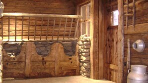 L’intérieur d’une cabane en rondins, avec un mur en pierre, une porte en bois et un conteneur en métal.