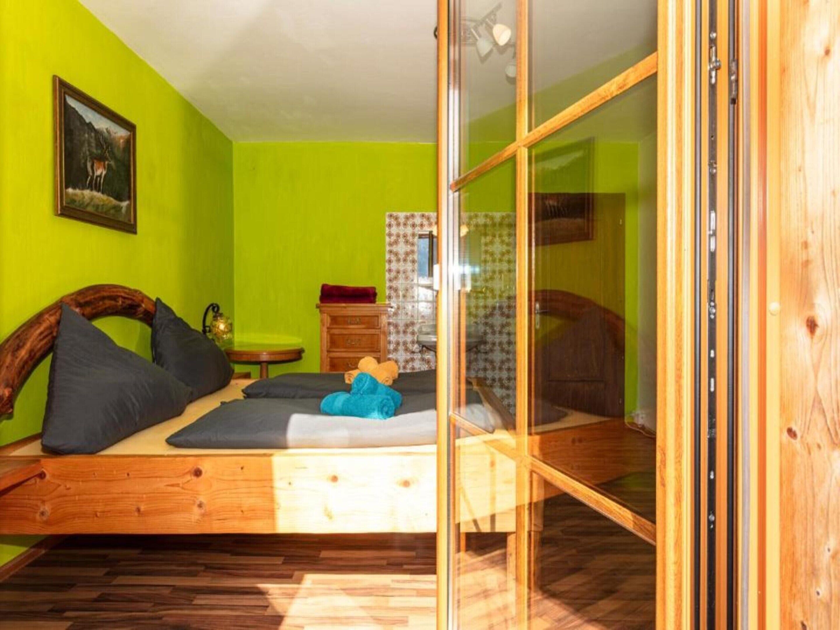 Una habitación con una cama, una mesita y suelo de madera.