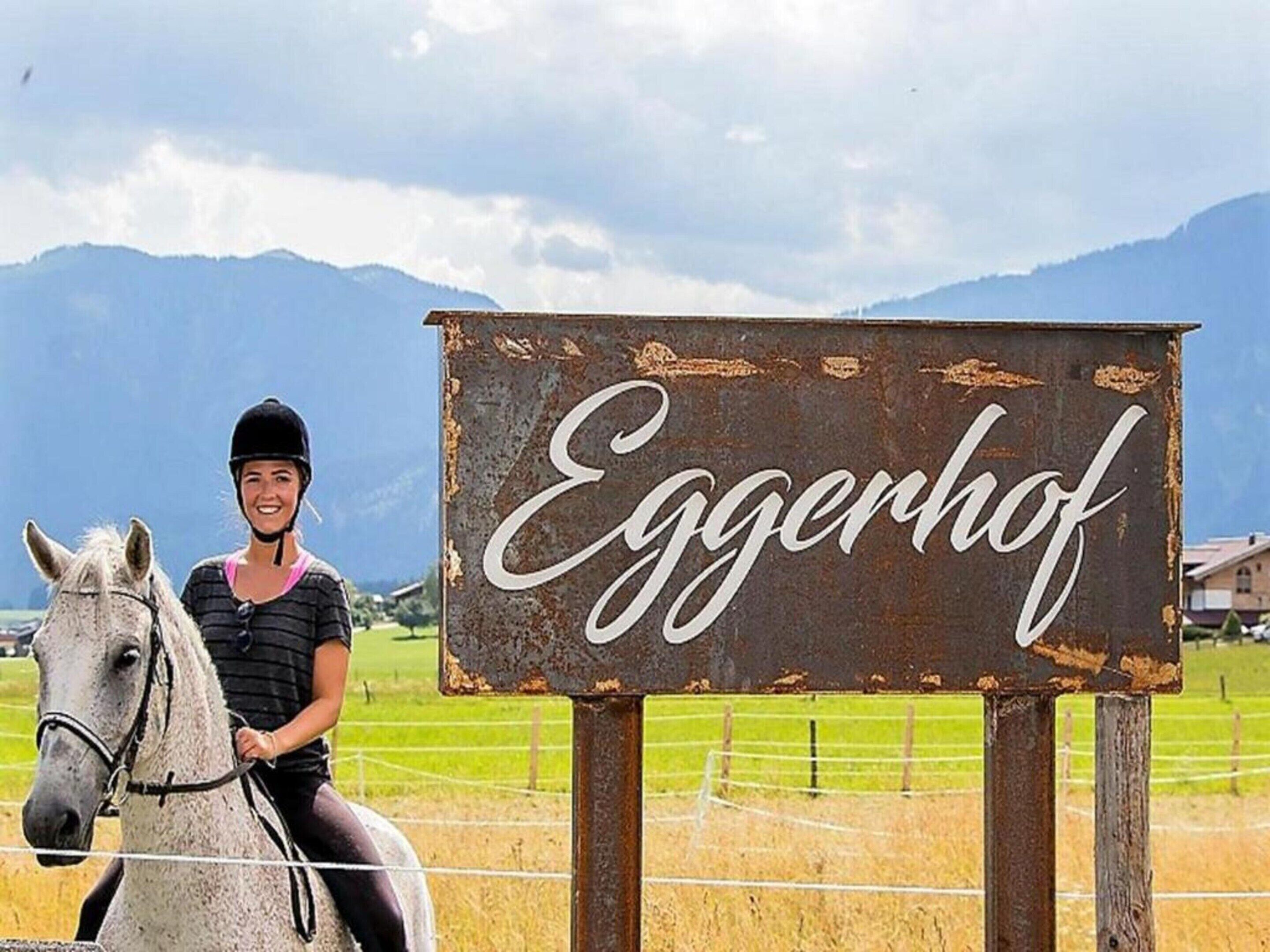 Una persona montando a caballo frente a un letrero que dice 'Eggerhof'.