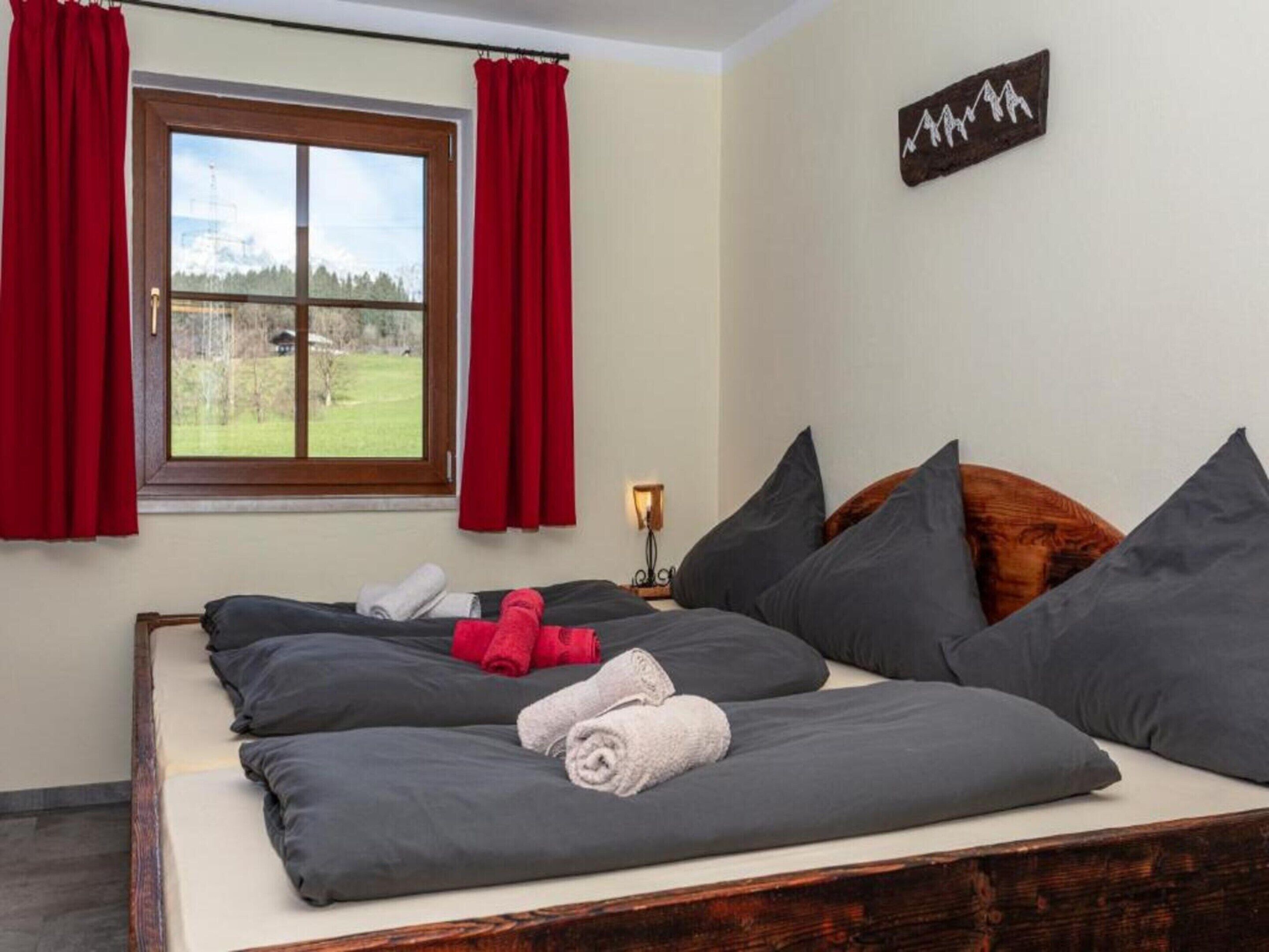 Ein Schlafzimmer mit Bett, roten Vorhängen, einem Fenster mit Blick und einem an der Wand befestigten Schild.