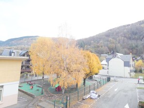 A parking lot with a playground, a red sculpture, and a white car. - Quiet apartment with balcony - 4 guests (Saint-Lary-Soulan)