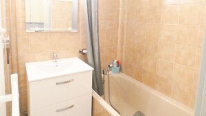 Un baño con lavamanos blanco, un espejo y una zona de ducha.