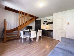 Een gezellig, compact verblijf met een eethoek, kitchenette en een trap.