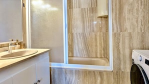 Ein Badezimmer mit einer Badewanne, einem Waschbecken und einer Waschmaschine.