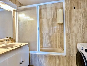 A bathroom with a bathtub, a sink, and a washing machine. - Apartment with jacuzzi - 6 guests (Tossa de Mar)
