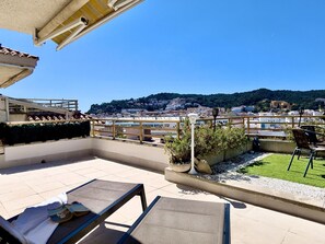 A rooftop terrace with outdoor seating, a view of a coastal city, and a hillside in the background. - Apartment with jacuzzi - 6 guests (Tossa de Mar)
