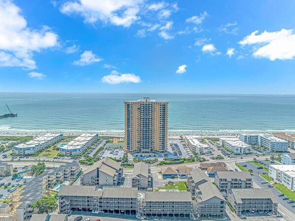 Un quartier résidentiel situé sur la côte, caractérisé par un immeuble de grande hauteur remarquable, un port de plaisance et une plage.