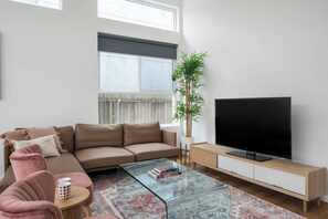 A modern living room with a sofa, coffee table, television, and a large window. - 5 Springside Rozelle (Rozelle)