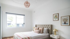 A bedroom with a bed, a nightstand, a lamp, and two framed pictures on the wall. - 5 Springside Rozelle (Rozelle)