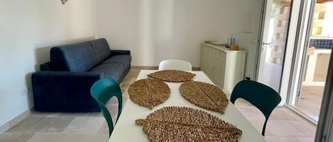 Un salon moderne comprenant un canapé, des fauteuils, une table à manger et des sets de table décoratifs en fibres tressées.
