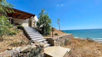 Una proprietà costiera con una scala in pietra che conduce a una casa con tetto in legno, con vista sul mare.