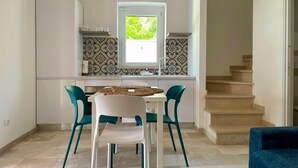 Een moderne keuken met een eethoek, met een witte tafel en stoelen, een raam met uitzicht, en een trap.