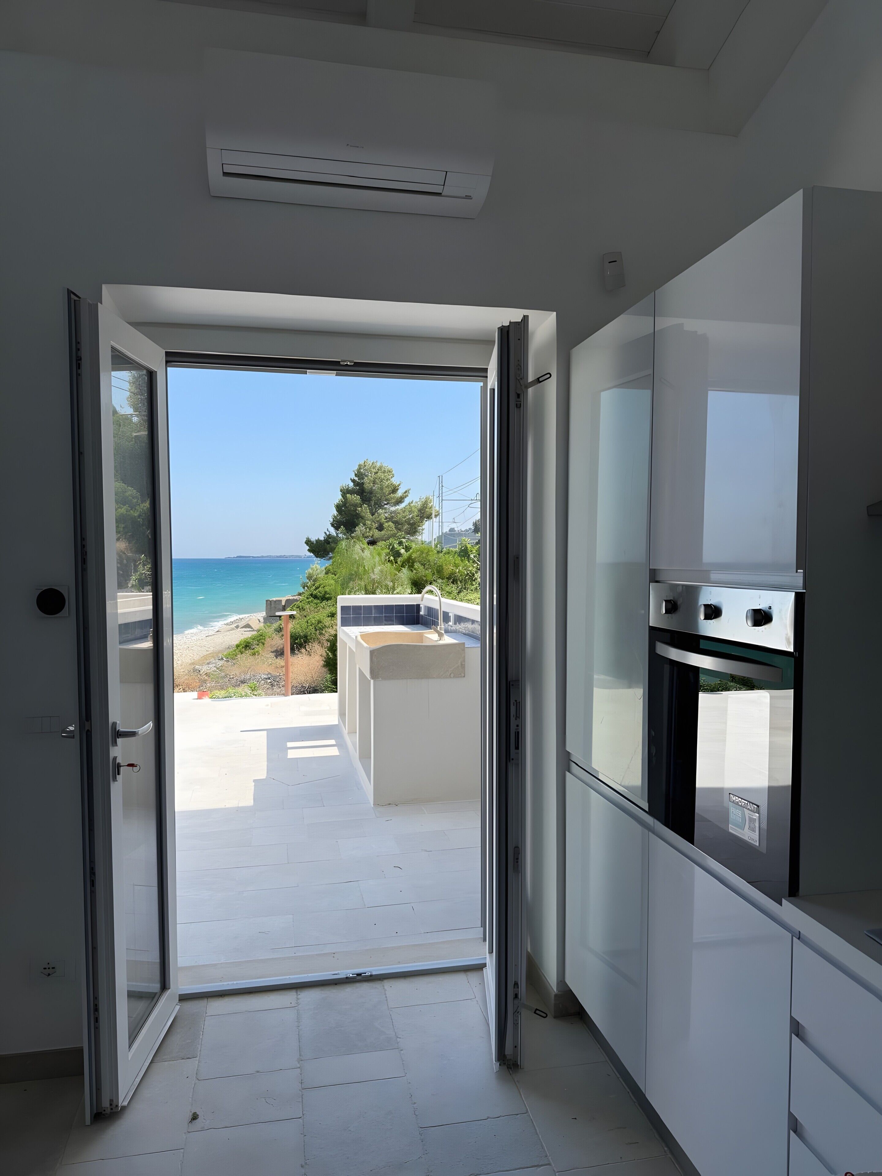 Una cucina con vista sul mare attraverso una porta aperta.