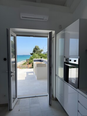 A kitchen with a view of the sea through an open door.