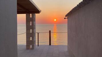 Un corridoio che conduce a un balcone con vista sul mare al tramonto.