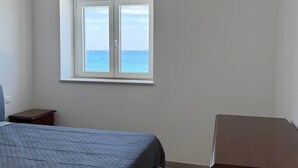 Een slaapkamer met een bed, een raam, een kaptafel en een nachtkastje.