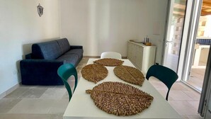 Ein modernes Wohnzimmer mit einer Couch, Sesseln, einem Esstisch und dekorativen, gewebten Untersetzern.