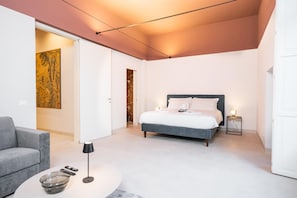 A modern bedroom with a bed, a bedside table, a lamp, and a painting on the wall. - Stemma Apartment   Loggiato Verga (SIRACUSA)