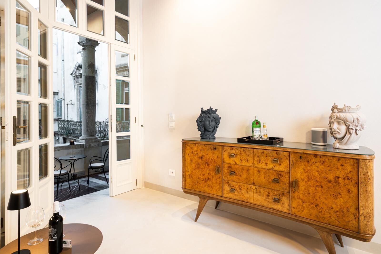 A room with a wooden cabinet, a wine bottle, and a glass on a table.