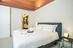 Una habitació d'hotel amb llit, taulella de nit i mirall.