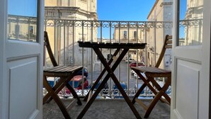 Un balcon offrant une vue sur des bâtiments historiques et un ciel d’un bleu éclatant.