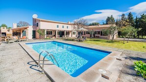 A swimming pool with a metal ladder, surrounded by a patio area with outdoor furniture.