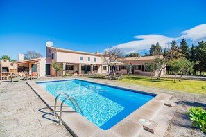 A swimming pool with a metal ladder, surrounded by a patio area with outdoor furniture.