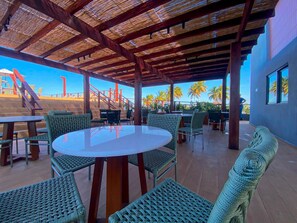 An outdoor seating area with wicker furniture and a clear view of palm trees and a staircase. - Smeralda Del Mare por Yolo (Ipojuca)