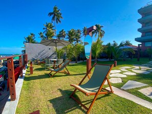 Zwembadgedeelte van een resort met ligbedden, een tafel en parasols.