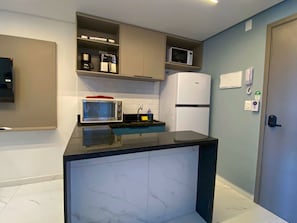 A compact kitchen with a microwave, a coffee maker, and a refrigerator. - Smeralda Del Mare por Yolo (Ipojuca)