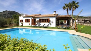 A two-story house with a swimming pool, a covered patio, and a mountain backdrop. - Contemporary Mallorcan Villa for 6 (Pollença)
